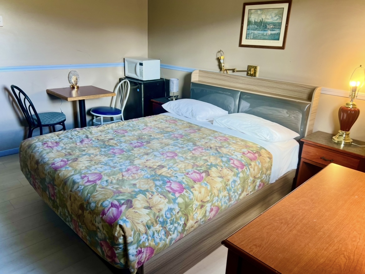Single room with one queen bed, a table and a mini-fridge